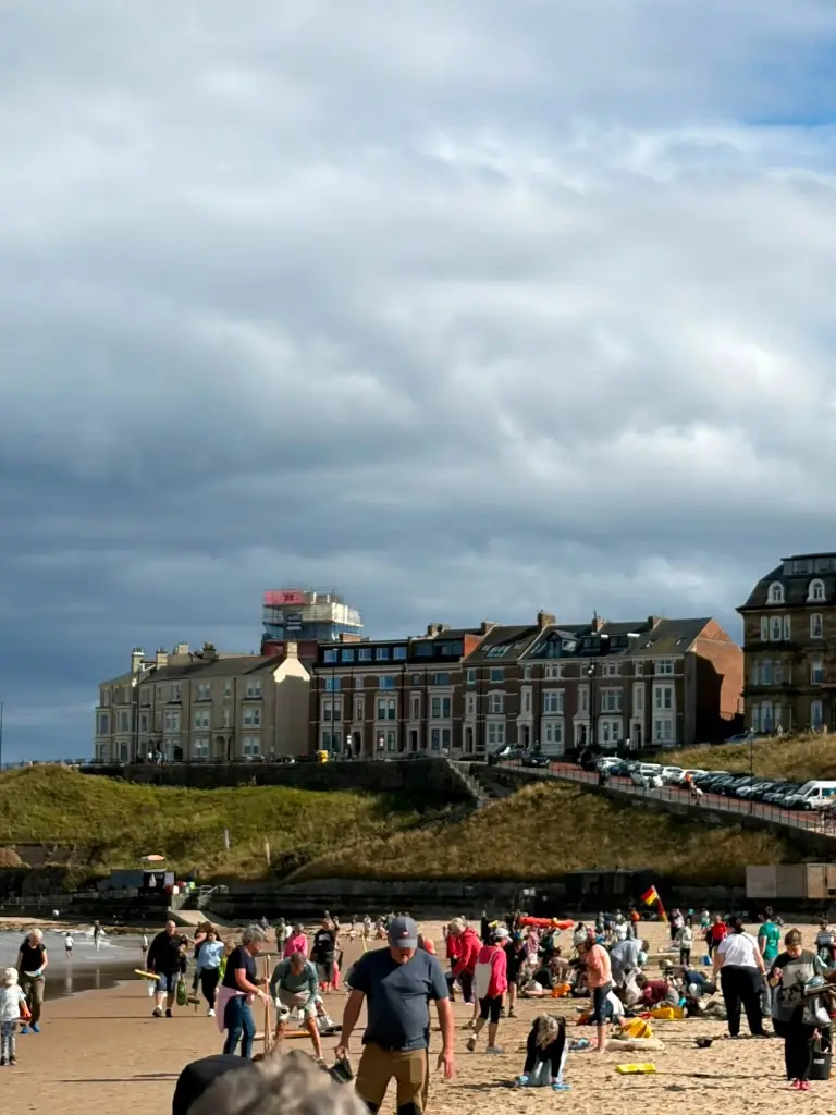 Crowd of volunteers on the beach with terrace houses on the cliff behind
