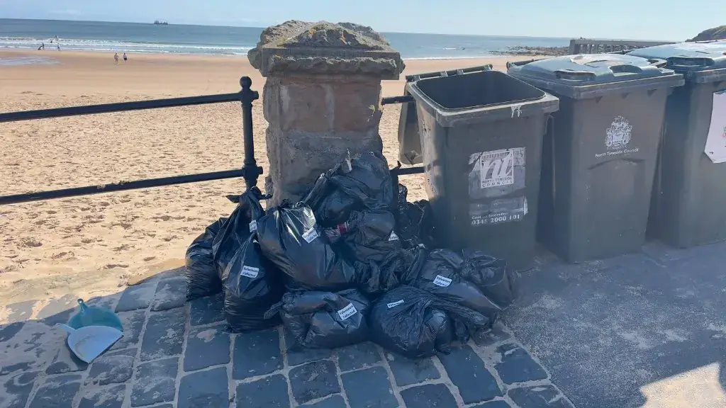 Pile of black bags labelled Volunteers Collected next to council bins on the promenade